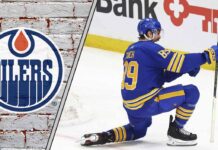 Alex Tuch celebrating a goal with the Edmonton Oilers logo to the left signifying the NHL trade rumor