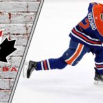 Evan Bouchard’s Olympic Dream on Thin Ice: Can the Oilers’ Defenseman Rebound for Team Canada? Edmonton Oilers defenseman Evan Bouchard looking concerned on the ice during a game, with Team Canada logo subtly in background.