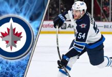 Close-up action shot of Winnipeg Jets defenseman Dylan Samberg skating with the puck during an NHL game.