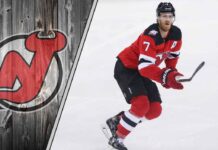 New Jersey Devils defenseman Dougie Hamilton skates with the puck, looking up ice during an NHL game, illustrating the NHL trade rumors discussion.