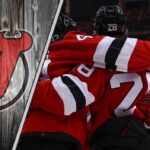 An action shot of the New Jersey Devils team celebrating a goal, illustrating their ambition for a deep playoff run and potential trade reinforcements.