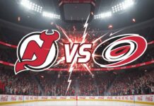 An image showing the New Jersey Devils logo on the left and the Carolina Hurricanes logo on the right, with a "VS" in explosive text between them, set against the backdrop of a packed ice hockey arena with bright spotlights and "Coca-Cola" logos on the rink boards