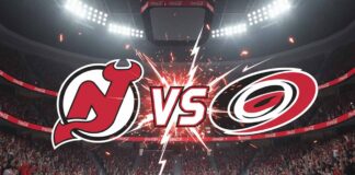 An image showing the New Jersey Devils logo on the left and the Carolina Hurricanes logo on the right, with a "VS" in explosive text between them, set against the backdrop of a packed ice hockey arena with bright spotlights and "Coca-Cola" logos on the rink boards