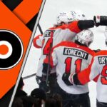 The Philadelphia Flyers team celebrating a goal on the ice, showcasing their teamwork and determination.