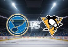 A wide-angle, stylized image featuring the St. Louis Blues logo on the left and the Pittsburgh Penguins logo on the right, with a "VS" graphic in between them, all set against a spotlight-illuminated interior of an empty hockey arena with a large jumbotron above center ice.