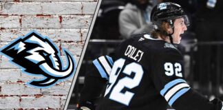 Utah Mammoth forward Logan Cooley skates with the puck, looking determined, during a game, illustrating his focus on a larger contract.