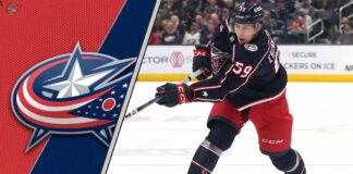 Columbus Blue Jackets forward Yegor Chinakhov skates with the puck during an NHL game, with the Blue Jackets logo visible in the background.