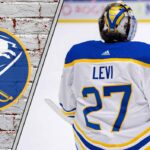 Buffalo Sabres goalie Devon Levi looks on from the net during an NHL game, contemplating his future.