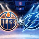 Can McDavid Rally the Oilers? How to Watch Oilers at Lightning Tonight (Nov 20) A wide-angle view inside a crowded hockey arena, featuring large, illuminated Edmonton Oilers and Tampa Bay Lightning logos colliding at center ice with a stylized metallic "VS" between them.