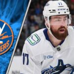 Filip Hronek of the Vancouver Canucks skating with the puck against the New York Islanders defense.