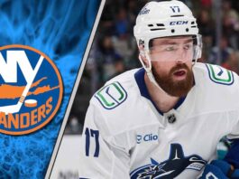 Filip Hronek of the Vancouver Canucks skating with the puck against the New York Islanders defense.