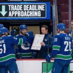 Vancouver Canucks players on the ice discussing strategy, representing the team entering trade deadline sell mode.