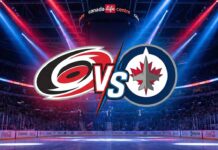 Stylized graphic showing the Carolina Hurricanes logo and Winnipeg Jets logo colliding with a "VS" between them, spotlighted over center ice inside a packed Canada Life Centre arena.