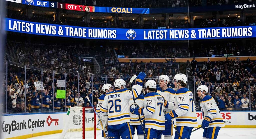 A photograph of the Buffalo Sabres players celebrating a goal on the ice at KeyBank Center, with a large digital banner above them on the Jumbotron displaying the text "LATEST NEWS & TRADE RUMORS." The scoreboard indicates a 3-1 lead for Buffalo over Ottawa.