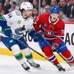Vancouver Canucks winger Kiefer Sherwood skating against Montreal Canadiens forward Zach Bolduc during an NHL game.