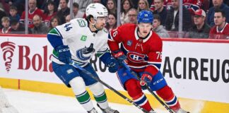 Vancouver Canucks winger Kiefer Sherwood skating against Montreal Canadiens forward Zach Bolduc during an NHL game.