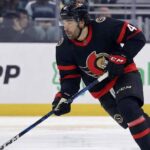 Ottawa Senators forward Kiefer Sherwood skating with the puck during an NHL game, wearing the team's black home uniform with red and white trim.
