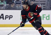 Ottawa Senators forward Kiefer Sherwood skating with the puck during an NHL game, wearing the team's black home uniform with red and white trim.