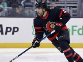 Ottawa Senators forward Kiefer Sherwood skating with the puck during an NHL game, wearing the team's black home uniform with red and white trim.