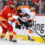 Philadelphia Flyers center Trevor Zegras (46) and Calgary Flames center Nazem Kadri (91) battle for the puck along the boards during an NHL game.