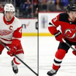 Quinn Hughes Trade Rumors: Devils and Red Wings Emerging as Top Suitors A split-screen image shows Quinn Hughes in two different jerseys. On the left, he is wearing a red and white Detroit Red Wings home jersey. On the right, he is wearing a red, black, and white New Jersey Devils home jersey.