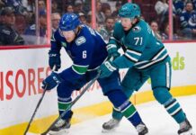 Vancouver Canucks forward Brock Boeser (#6) and San Jose Sharks forward Macklin Celebrini (#71) battle for the puck along the boards during an NHL game.