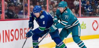 Vancouver Canucks forward Brock Boeser (#6) and San Jose Sharks forward Macklin Celebrini (#71) battle for the puck along the boards during an NHL game.