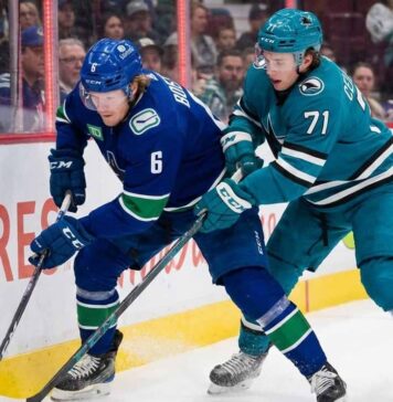 Vancouver Canucks forward Brock Boeser (#6) and San Jose Sharks forward Macklin Celebrini (#71) battle for the puck along the boards during an NHL game.