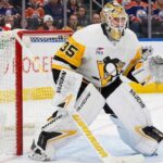 Pittsburgh Penguins goaltender Tristan Jarry, wearing his white number 35 away jersey and gear, in his stance in the goal crease at Rogers Place, with Edmonton Oilers branding visible on the boards behind him.