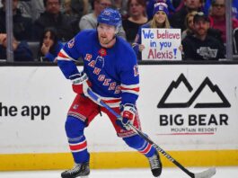 Why Trading Alexis Lafrenière Is Harder Than the New York Rangers Thought New York Rangers forward Alexis Lafrenière, wearing his blue home uniform, skates with the puck during a game. In the background behind the glass, a female fan holds a handwritten sign that reads, "We believe in you Alexis!".