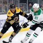 David Pastrnak of the Boston Bruins and Jason Robertson of the Dallas Stars battle for the puck along the boards during an NHL game.