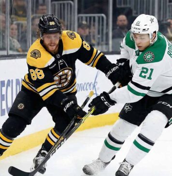 David Pastrnak of the Boston Bruins and Jason Robertson of the Dallas Stars battle for the puck along the boards during an NHL game.