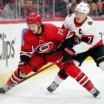 How to Watch Hurricanes at Senators: TV Schedule, Odds & Prediction Carolina Hurricanes forward Sebastian Aho (#20) in a red jersey battling with Ottawa Senators captain Brady Tkachuk (#7) in a white jersey for puck possession along the rink boards during an NHL game.