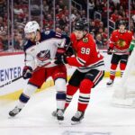 How to Watch Blue Jackets at Blackhawks: TV, Odds & Prediction (Is Chicago Upset Ready?) Columbus Blue Jackets' Adam Fantilli (#11) and Chicago Blackhawks' Connor Bedard (#98) battle for the puck along the boards in the Blackhawks' defensive zone during a game at the United Center, with a Blackhawks goaltender visible in the background.