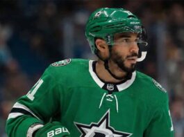 Is Evander Kane the Missing Piece for the Dallas Stars’ Cup Run? Close-up photograph of NHL player Evander Kane on the ice, wearing a green Dallas Stars home jersey with the number 91 visible on the sleeve, a green Stars helmet, and gloves. He is looking toward the right side of the frame with a white mouthguard hanging from his mouth. Blurred spectators fill the background stands.