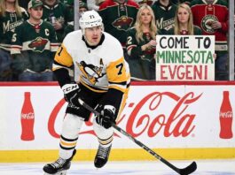 The Reality of an Evgeni Malkin Trade: Will the Penguins Legend Actually Move? Pittsburgh Penguins center Evgeni Malkin (71) skates with the puck during an away game. Behind him behind the glass, Minnesota Wild fans hold a handmade sign that reads "COME TO MINNESOTA EVGENI" above Coca-Cola advertisements on the boards.