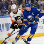 Buffalo Sabres defenseman Rasmus Dahlin and Philadelphia Flyers forward Trevor Zegras battle for the puck along the boards during an NHL game.
