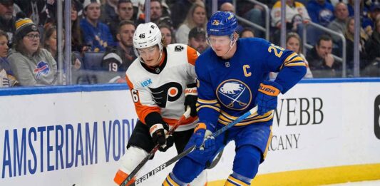 Buffalo Sabres defenseman Rasmus Dahlin and Philadelphia Flyers forward Trevor Zegras battle for the puck along the boards during an NHL game.
