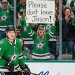Why The Pittsburgh Penguins Are All-In On Jason Robertson Dallas Stars forward Jason Robertson skates on the ice while a female fan behind the glass holds a handwritten sign that reads, 'Please don't leave Jason!'.