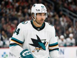Concept image of Vancouver Canucks forward Kiefer Sherwood celebrating fiercely on the ice while wearing a teal San Jose Sharks away jersey.