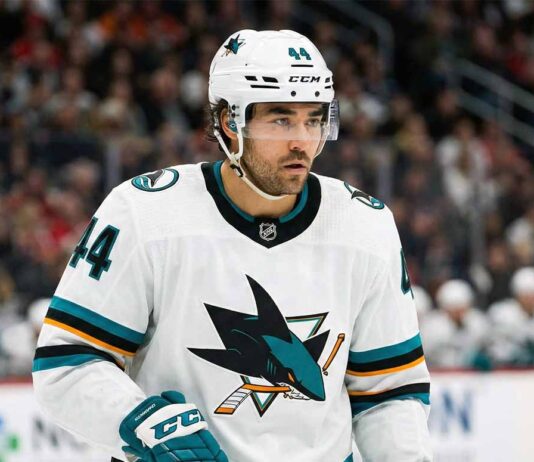Concept image of Vancouver Canucks forward Kiefer Sherwood celebrating fiercely on the ice while wearing a teal San Jose Sharks away jersey.