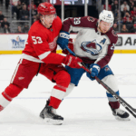 Avalanche vs Red Wings TV Schedule: Why You Can’t Miss This Saturday Matinee Clash Detroit Red Wings defenseman Moritz Seider (53) in a red home jersey and Colorado Avalanche forward Nathan MacKinnon (29) in a white and maroon away jersey battle fiercely for the puck along the boards during an NHL game at Little Caesars Arena.