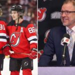Devils Crisis: Inside the Search for a Savior After Humiliating Defeat A split-screen photograph. On the left side, two New Jersey Devils hockey players, wearing red number 91 and number 86 jerseys, smile while standing on the ice holding their sticks. On the right side, New Jersey Devils General Manager Tom Fitzgerald, wearing a navy suit and glasses, speaks into a microphone at a podium inside the Prudential Center, with Devils and MSG logos in the background.