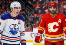 Historic Milestones & A Shocking Trade: The NHL Landscape Shifted Overnight A split-screen hockey photograph comparing contrasting moods. On the left side, Ryan Nugent-Hopkins of the Edmonton Oilers, wearing a white away jersey, is yelling in celebration with his mouth wide open. On the right side, Nazem Kadri of the Calgary Flames, wearing a red home jersey, looks forward with a serious, stoic expression.