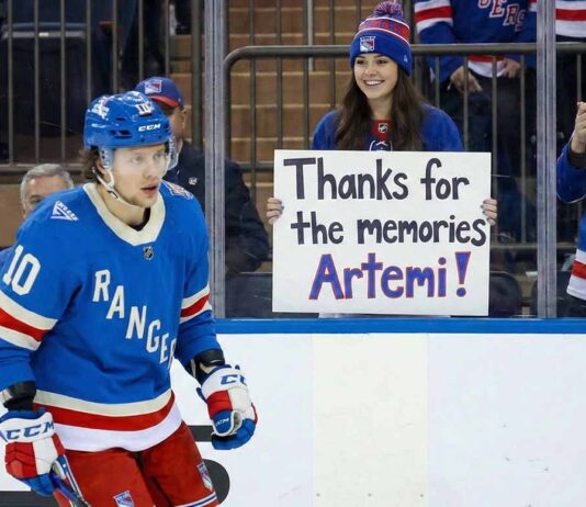New York Rangers player Artemi Panarin #10 skates on the ice while a smiling female fan behind the glass holds a handwritten sign that reads, "Thanks for the memories Artemi!".