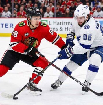 Why You Can’t Miss Bedard vs. Kucherov: Lightning at Blackhawks TV & Streaming Guide Chicago Blackhawks center Connor Bedard (98) in a red home jersey and Tampa Bay Lightning winger Nikita Kucherov (86) in a white away jersey battle fiercely for puck possession with their sticks crossed during an NHL game at the United Center.
