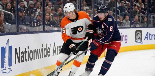 Can the Rested Blue Jackets Bury the Flyers in Tonight’s Metro Clash? Philadelphia Flyers forward Trevor Zegras (#46) in a white away jersey and Columbus Blue Jackets defenseman Zach Werenski (#8) in a navy home jersey battle for a loose puck against the boards during an NHL game at Nationwide Arena.