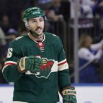 NHL center Vincent Trocheck depicted wearing a green Minnesota Wild home uniform, helmet, and gloves while on the ice during a game situation.