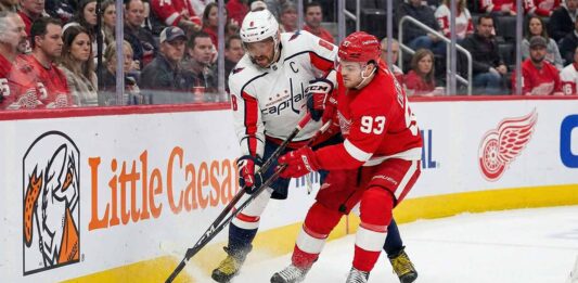 Can the Caps Bounce Back in Hockeytown? Capitals vs Red Wings Viewing Guide & Picks Washington Capitals' Alex Ovechkin (8) and Detroit Red Wings' Alex DeBrincat (93) battle for possession of the puck along the boards with their sticks engaged during an NHL game at Little Caesars Arena.
