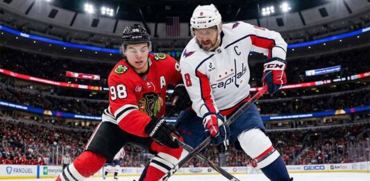 Chicago Blackhawks center Connor Bedard (#98) and Washington Capitals captain Alex Ovechkin (#8) battle fiercely for puck possession with their sticks on the ice during an NHL game at the United Center.